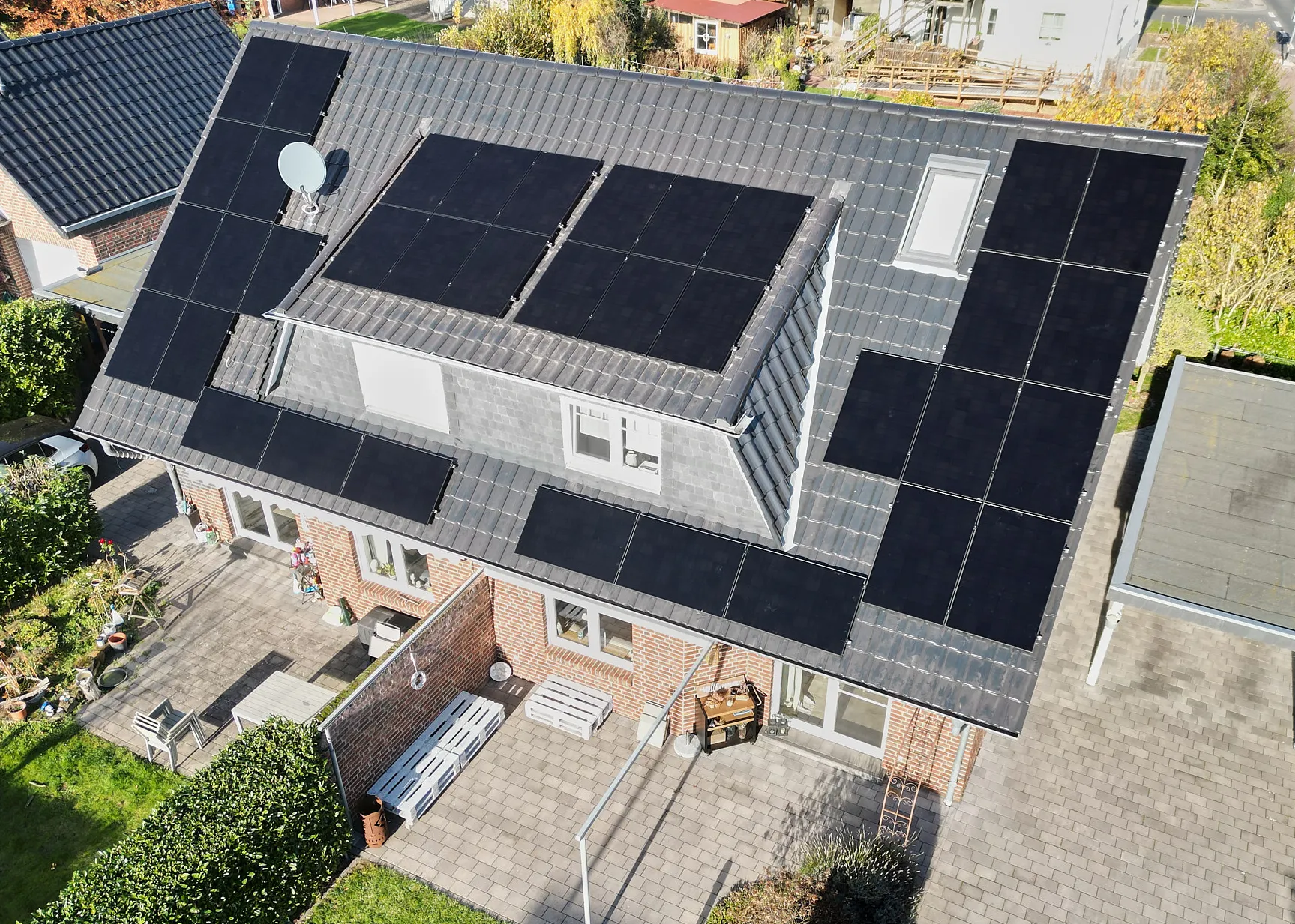 Drohnenaufnahme einer Photovoltaik-Anlage auf dem Dach eines Einfamilienhauses, vollständig belegt mit Solarmodulen.